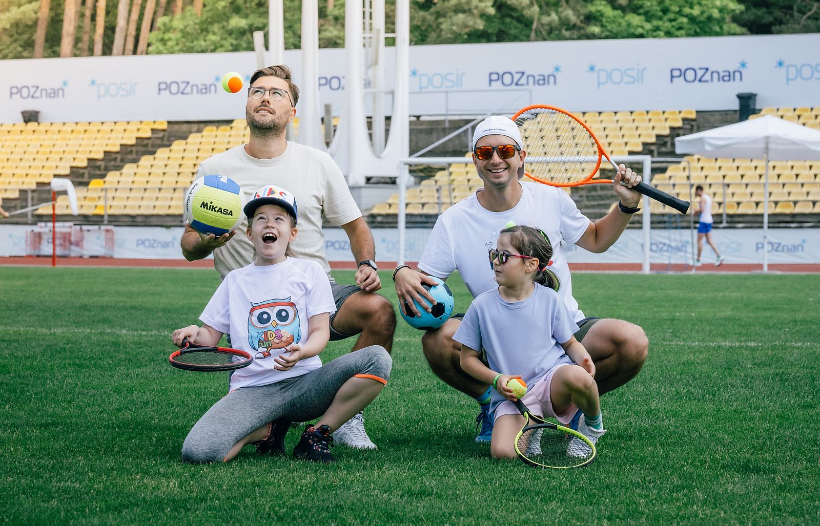 dw&oacute;ch mężczyzn z dw&oacute;jką dzieci na stadionie lekkoatletycznym